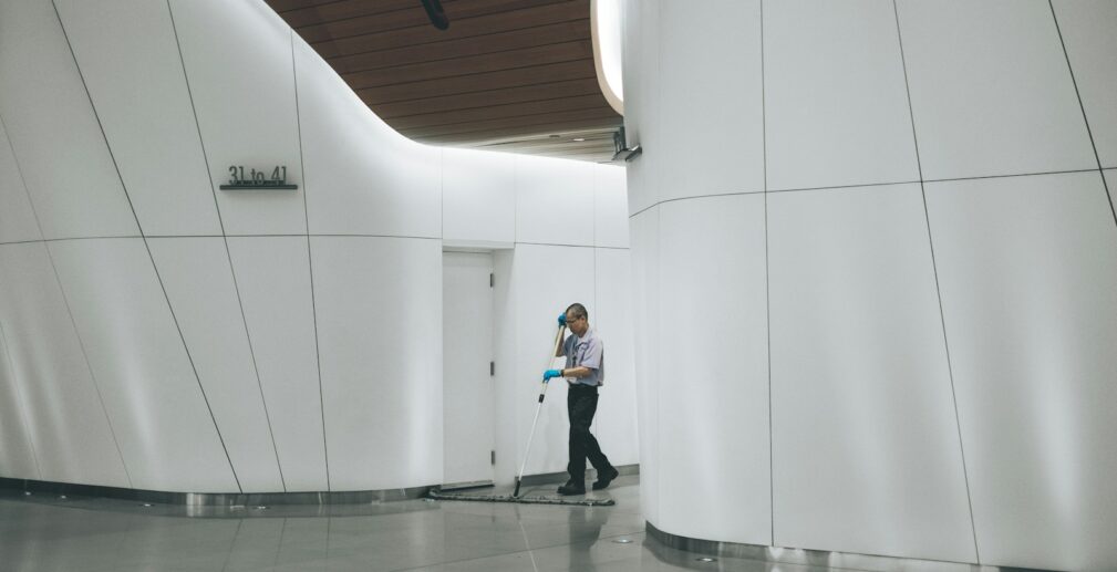 man cleaning on floor beside white wall