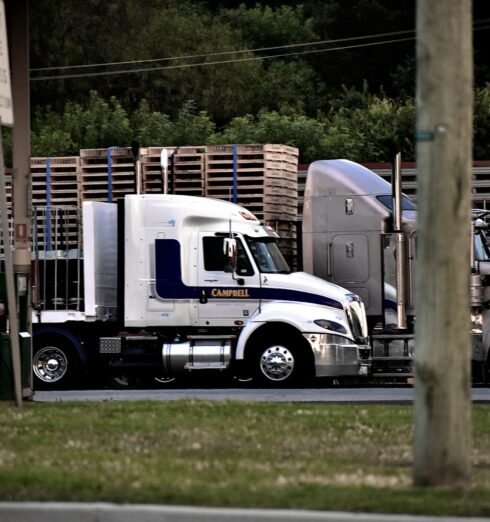 a semi truck driving down a street next to a wooden fence